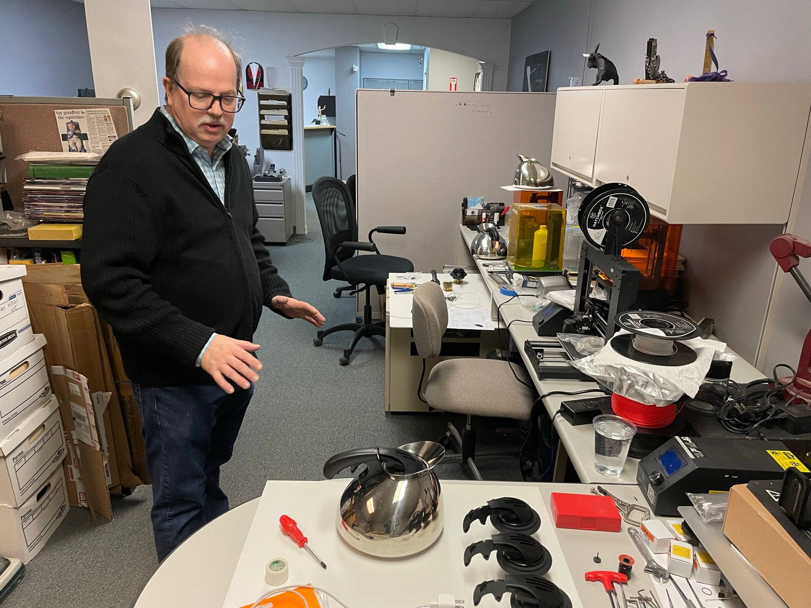 Prototype parts and kettle components arranged on a lab workbench